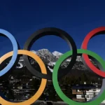 The Winter Olympics 2026 logo displayed in front of the Italian Alps.